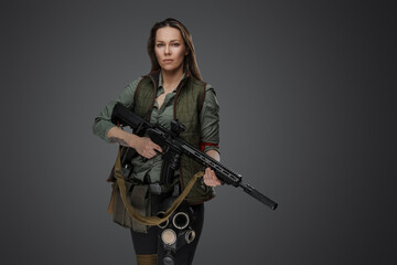 Studio shot of professional killer woman with rifle in setting of post apocalypse.
