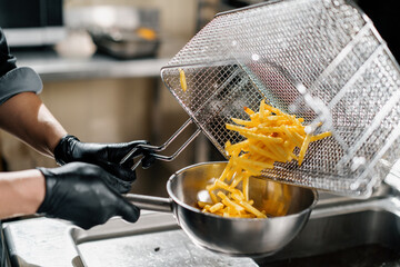 professional kitchen in the restaurant of the hotel the chef takes out delicious french fries from the fryer