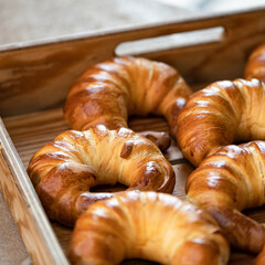 Croissants with stuffing in wooden tray. Fresh homemade pastries for tea. Rolled buns. French cuisine. Yeast dough. Close-up. View from above. Soft focus.