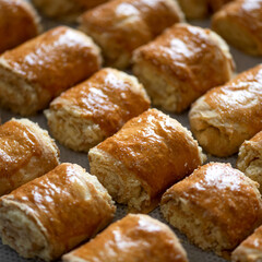 Small puff pastry rolls with cottage cheese filling on baking sheet. Fresh sweet pastry. Homemade sweets. Close-up. View from above. Soft focus.