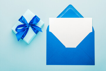 Blue gift box with a blue ribbon and a greeting blank with envelopes.Greeting card.