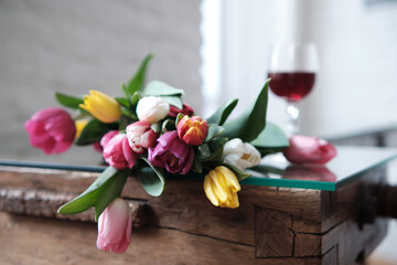A bouquet of tulips with a glass of wine. Spring flowers, International Womens Day.