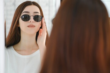 She made her choice. Beautiful young woman adjusting her new sunglasses and smiling while standing in optic store.