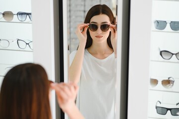 She made her choice. Beautiful young woman adjusting her new sunglasses and smiling while standing in optic store.