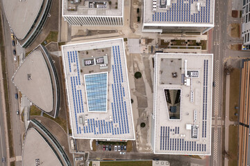 Drone photography of office rooftops and solar panels on them during cloudy spring day.