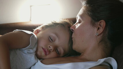 Obraz na płótnie Canvas Mother and child napping together lying on couch. Candid authentic parent asleep with son