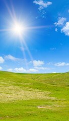 Hilly landscape and sun on sky. Vertical photo.