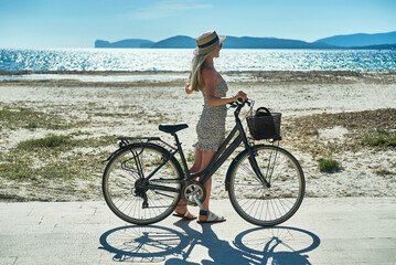 Carefree woman with bike riding on sand beach having fun