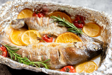 baked trout with lemon, orange, spices on a stone background