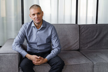 Portrait of a happy mid adult man sitting on the couch at home