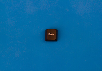 Button delete from computer keyboard isolated on blue background. One black button with the inscription delete lies on a blue background separately from the keyboard.