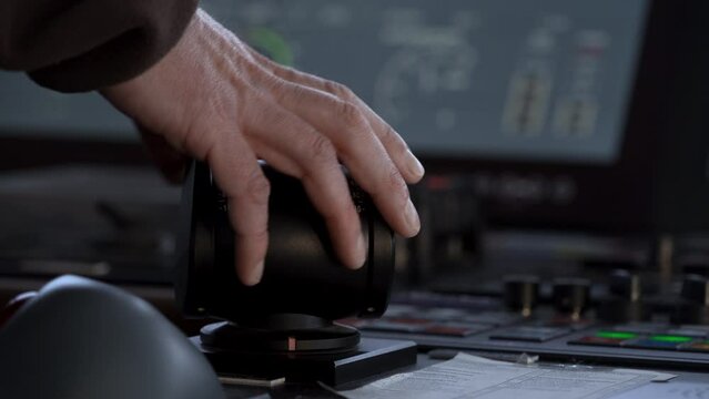 Hand turns azimuth controller. Vessel navigation bridge. Azipod control turns. Close-up. Control panel in background