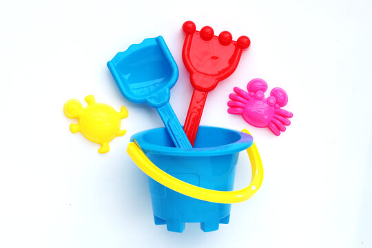 Plastic toys, shovels in bucket for sand on white background. Summer background concept
