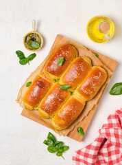 Rolled buns with basil pesto on a wooden board on a light concrete background. Unsweetened pastries, snack buns.