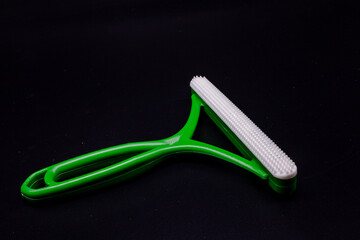 Plastic green pet hair removal with a black background. Pet hair brush with text area.