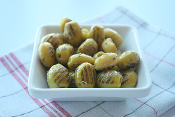 Grilled olives in a white plate on table 