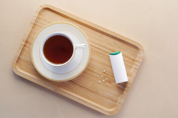 artificial sweetener container and tea cup on table 