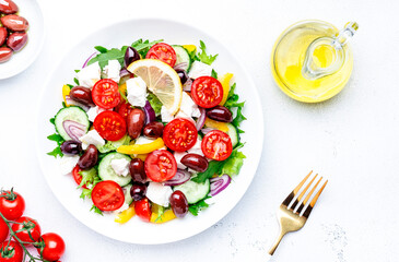 Greek salad with feta cheese, kalamata olives, cherry tomato, yellow paprika, cucumber and onion, healthy mediterranean diet food, low calories eating. White table background, top view