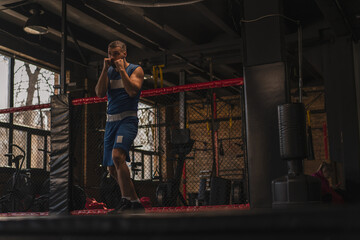 Obraz na płótnie Canvas A boxer in the gym who fights with the shadow practices punches