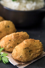 Bolinhos de bacalhau, very famous in Portuguese gastronomy. Fried dumpling, cod dumpling, fish, salted cod fritters, bacalao bunuelos. Codfish cake served with white rice on a dark background.