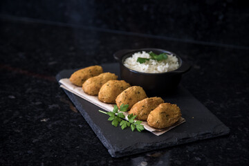 Bolinhos de bacalhau, very famous in Portuguese gastronomy. Fried dumpling, cod dumpling, fish, salted cod fritters, bacalao bunuelos. Codfish cake served with white rice on a dark background.