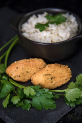 Bolinhos de bacalhau, very famous in Portuguese gastronomy. Fried dumpling, cod dumpling, fish, salted cod fritters, bacalao bunuelos. Codfish cake served with white rice on a dark background.