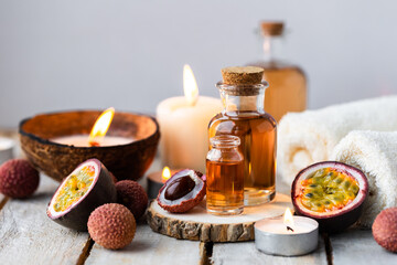 Glass bottles with pure organic essential litchi and passion fruit oil on wooden background. Concept of natural ingredients for beauty treatment, skin care, massage. Exotic fruits extract and essence