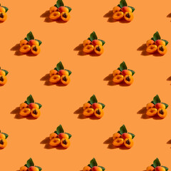 Pattern of ripe broken apricot berries with green leaf on orange background
