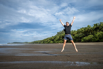 Fototapeta na wymiar Junger Mann springt am Playa Uvita im Parque Nacional Marino Ballena, Costa Rica