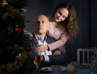 Young man sitting at festive New Year table offended after quarrel with wife