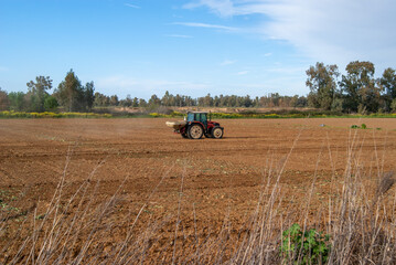 Tractor con voladora abonando un campo de cultivo.