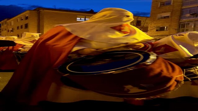 Soria, Spain - April 11, 2022: vertical video of a hooded brother playing the bass drum during the procession on Holy Monday in Holy Week