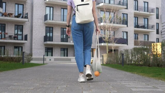 Woman supports ecology and vegetarianism, comes from the store with reusable cloth bags filled with vegetables.
