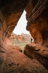 Young 30s woman steps out onto ledge in Subway Cave Boynton Canyon Az.