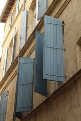 Typical façade of a building in Provence, France. Typical Provencal light blue shutters open against a cream colored building façade. Southern France windows open against stone building. Open windows