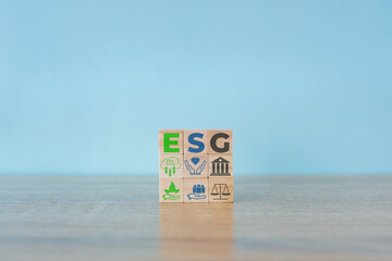 Wooden cubes with abbreviation  ESG icons on blue background. ESG concept of environmental, social...