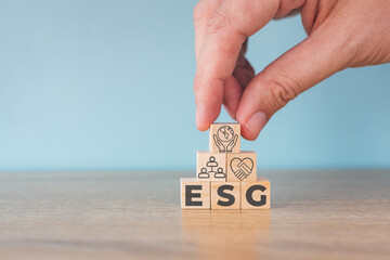 Wooden cubes with abbreviation  ESG icons on blue background. ESG concept of environmental, social and governance. Sustainable corporation development. Copy space.