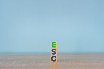 Wooden cubes with abbreviation  ESG icons on blue background. ESG concept of environmental, social...