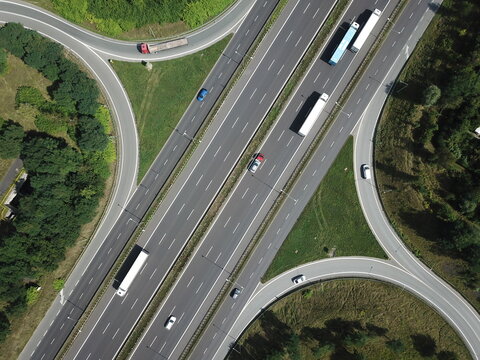 Aerial drone top down photo of a higway, asphalt roads in a city, trucks carrying cargo, birds eye view.