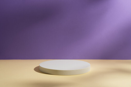Empty white round podium and shadows on light purple and yellow background. Showcase for product presentation. Pedestal for beauty cosmetic branding. Minimal still life in pastel colours. Copy space. © gorina_anna