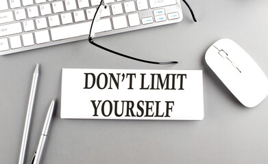 DON'T LIMIT YOURSELF text on paper with keyboard on grey background