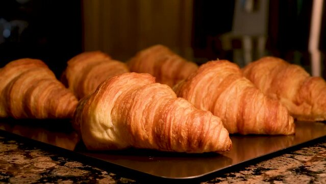 stone marble table baking sheet on it six freshly baked croissants camera slowly drives off breakfast in France Hand takes fresh golden French croissant from the baking sheet. Fresh classic pastries