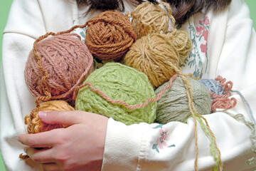 the girl holds skeins of colorful yarn in her hands. Hobi knitting yarn, handmade.