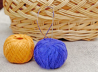 a needle with a blue and yellow thread stuck in a skein