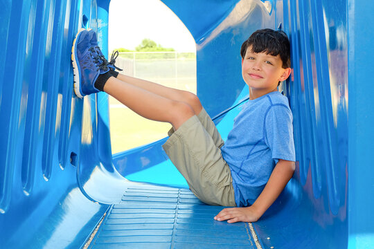Smiling young boy sitting on playground equipment outside on a sunny day - Powered by Adobe