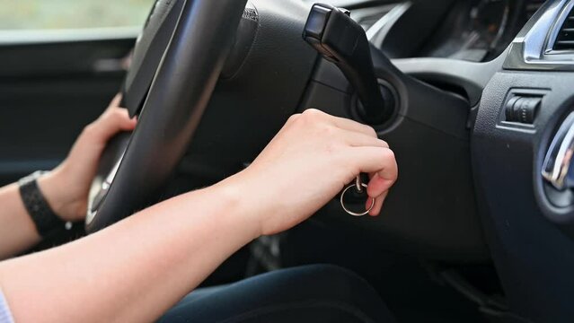 Woman's hand turns key and starts car engine