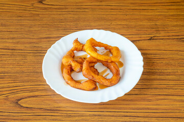 Picarones are ring-shaped fried sweets made with wheat flour dough mixed with squash, and sometimes sweet potato, bathed in flavored chancaca honey