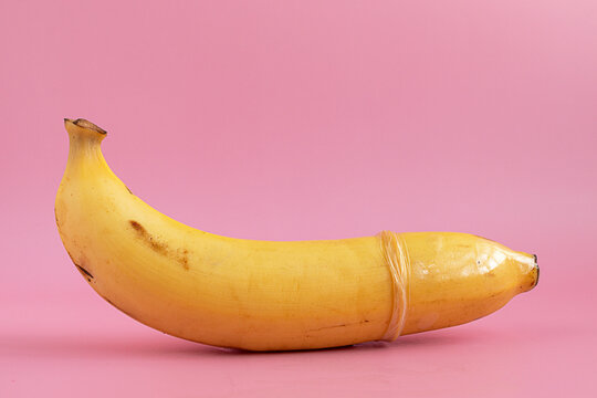 Condom on banana concept symbol of prevention of sexually transmitted diseases and pregnancy.