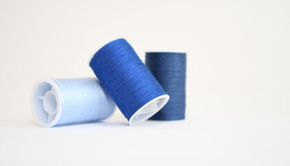 Three spools of blue yarn in different shades on a white background