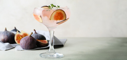 Glass of tasty fig lemonade on light background with space for text